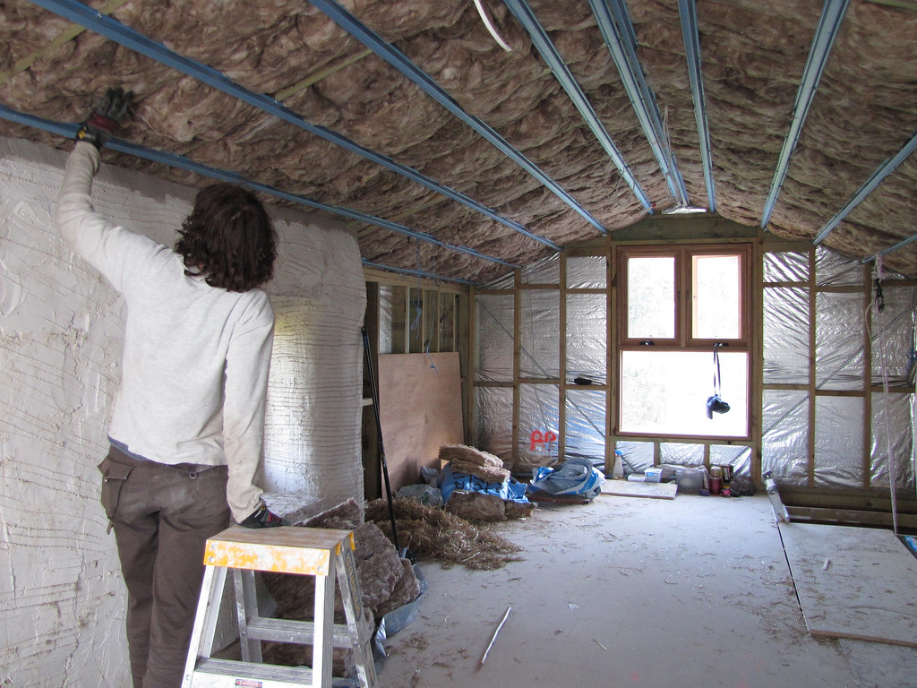 Pose d'isolant en laine minérale sous une toiture en cours de rénovation